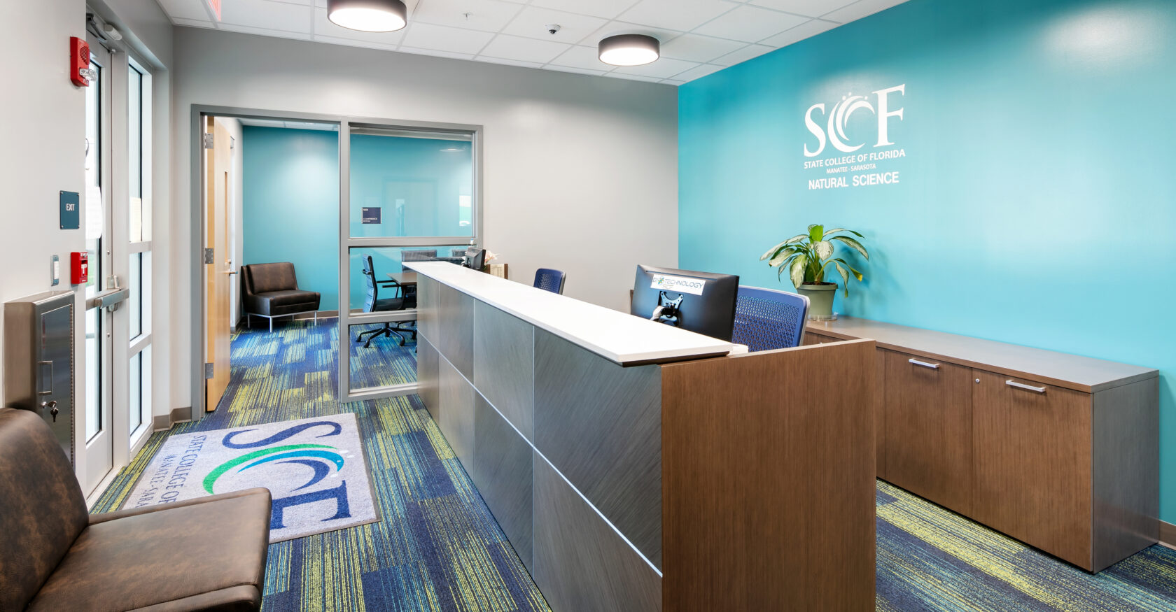 SCF Science building interior front desk image with SCF Science Logo on the back wall behind the desk